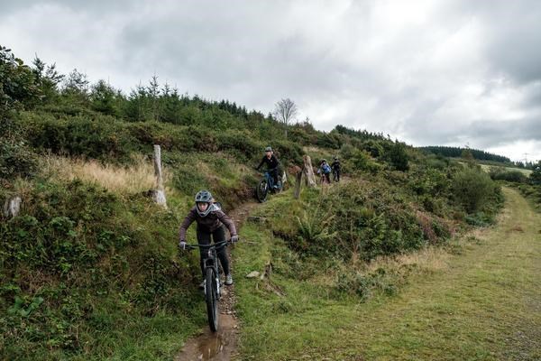group of rider descending penhyyd trail in afan